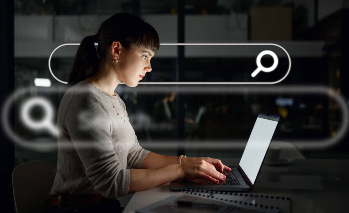 A woman working on a laptop with a digital search bar overlay, representing lawyer search engine optimization.