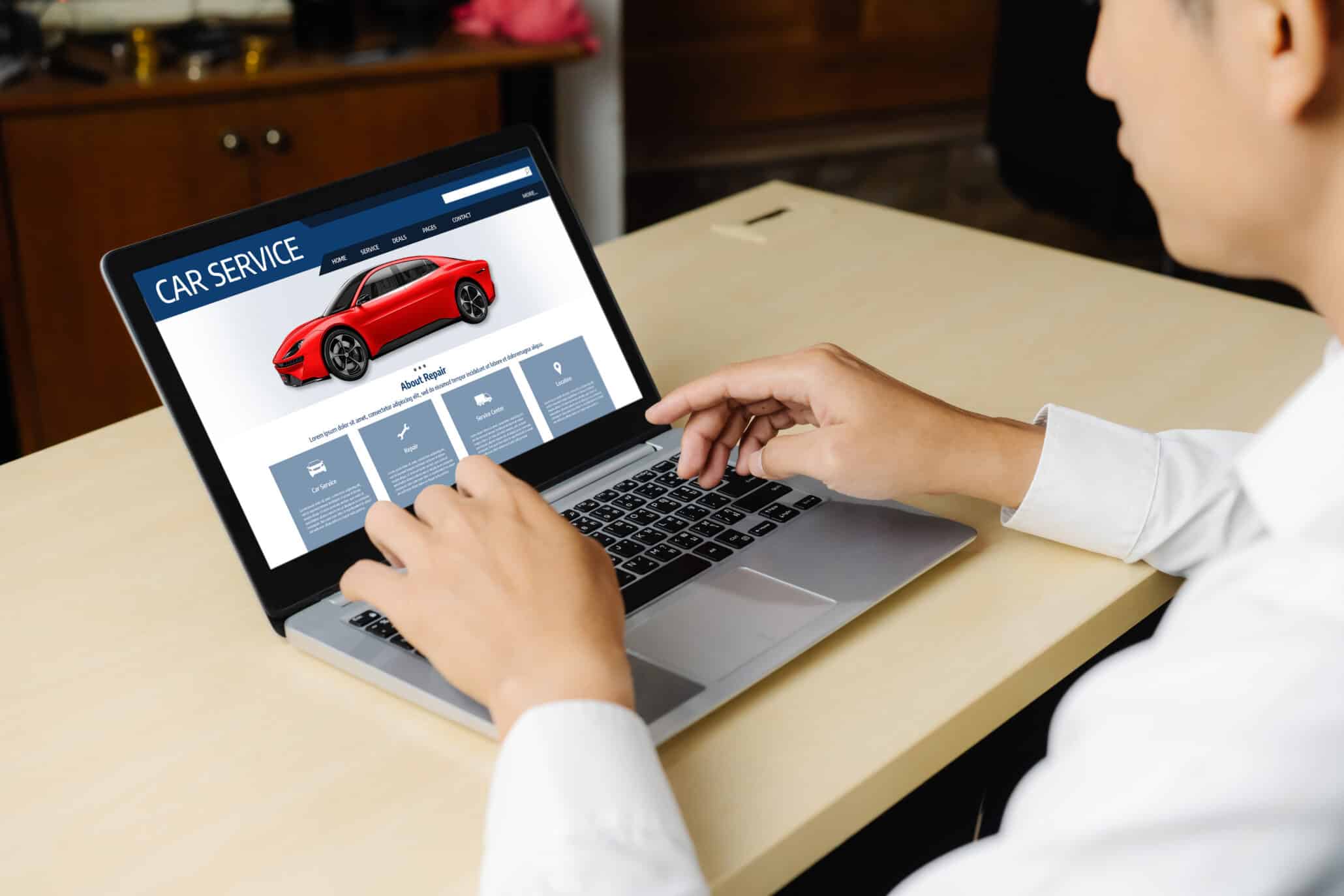 Person viewing a car service website with a red car and service options on a laptop