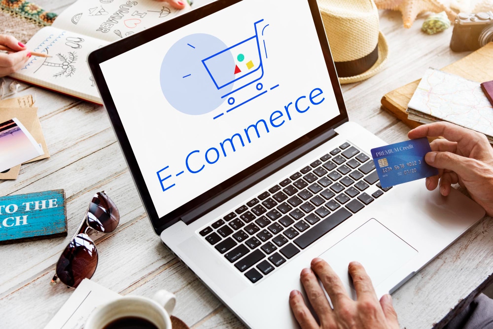 Person using laptop with ecommerce shopping cart icon while holding credit card for online purchase